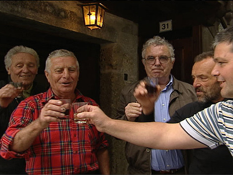 Männer beim Anstoßen mit Wein vor Osteria
