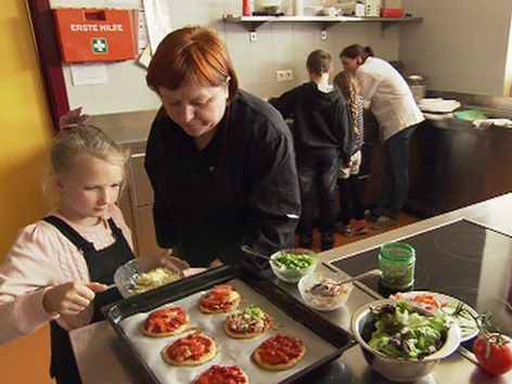 Kinder kochen gemeinsam mit Erwachsenen